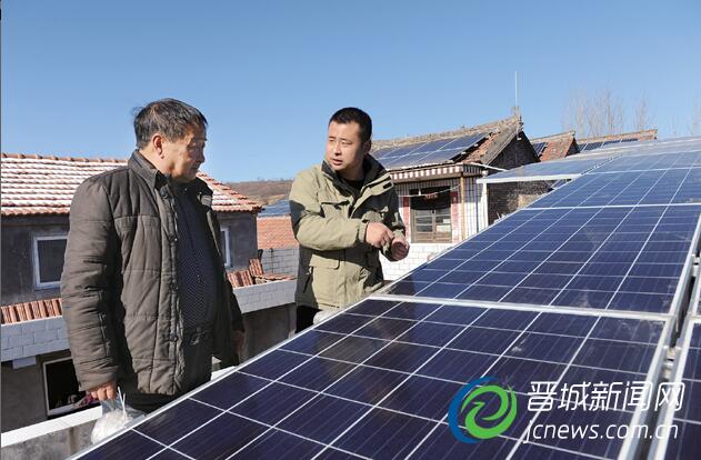 在農(nóng)戶家屋頂,葉拽與村民察看光伏發(fā)電板運(yùn)行情況。本報(bào)記者 張文庭 攝